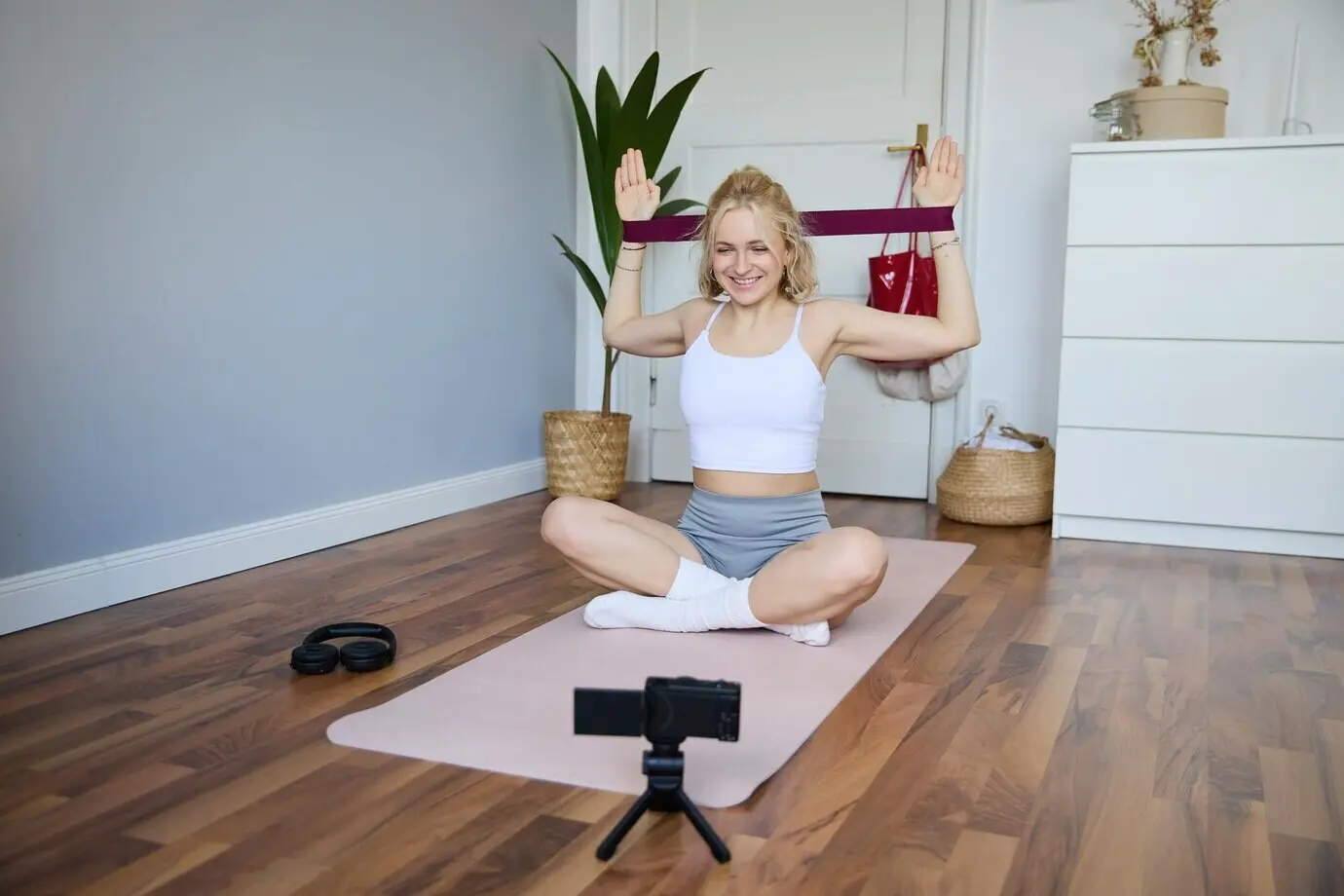 Porträt einer jungen, athletischen Frau, die zu Hause ein Workout-Video aufnimmt und Inhalte zu Sport und Fitness erstellt.